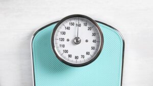 One bathroom scale on white wooden background, top view